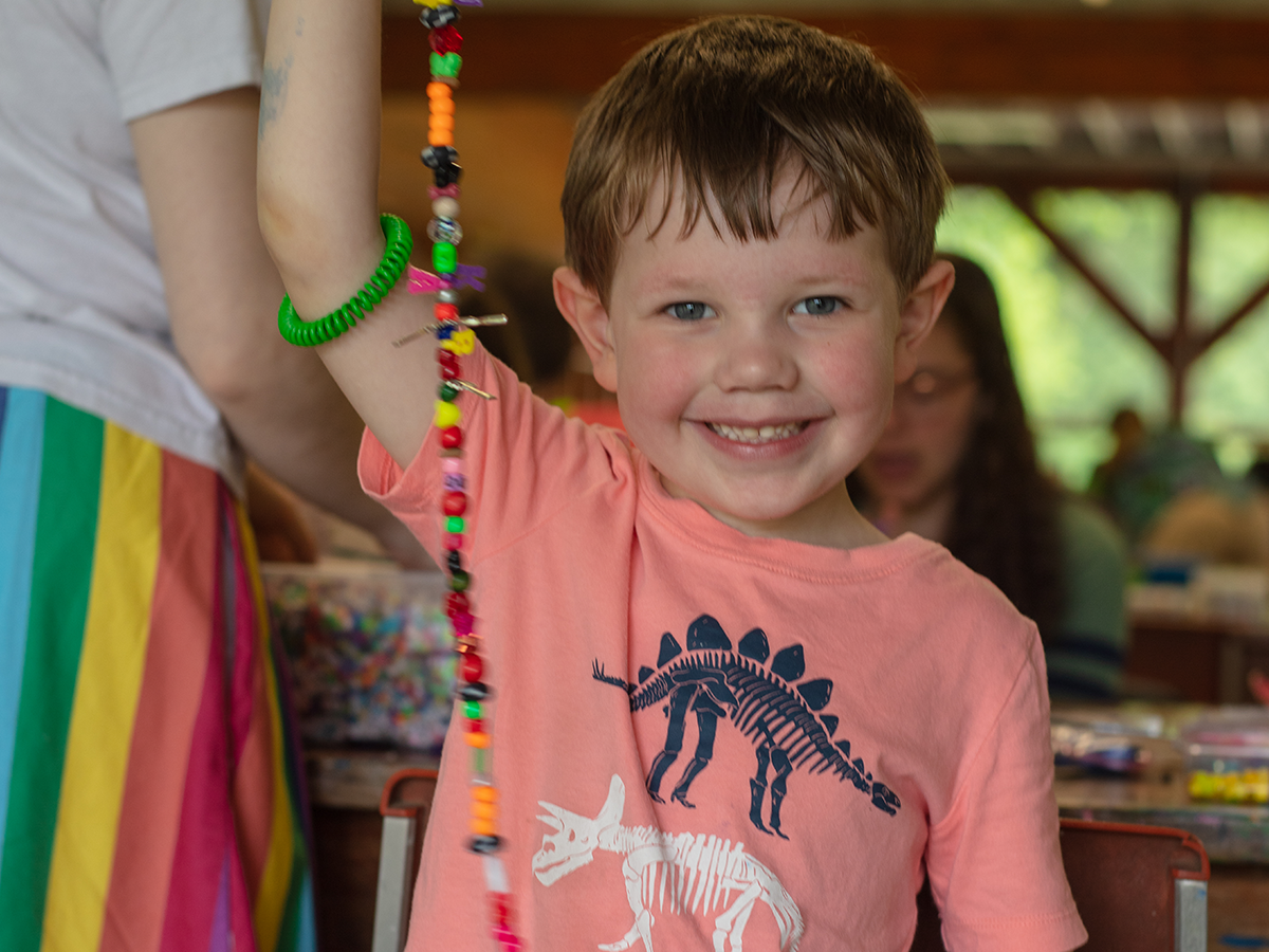 boy showing off beads at camp