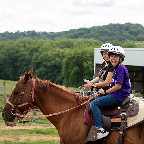 oncology camper girl laughing while riding a horse