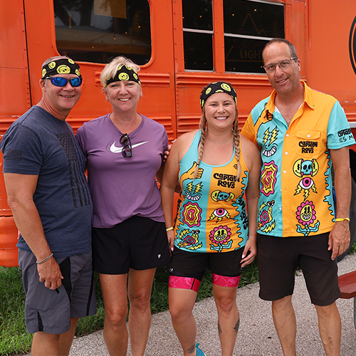 four jennas jam bike rider posing in front of orange bus